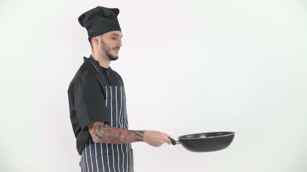 Fiatal férfi séf flipping zöldségek wok lassított felvételen fehér háttér - Felvétel, videó