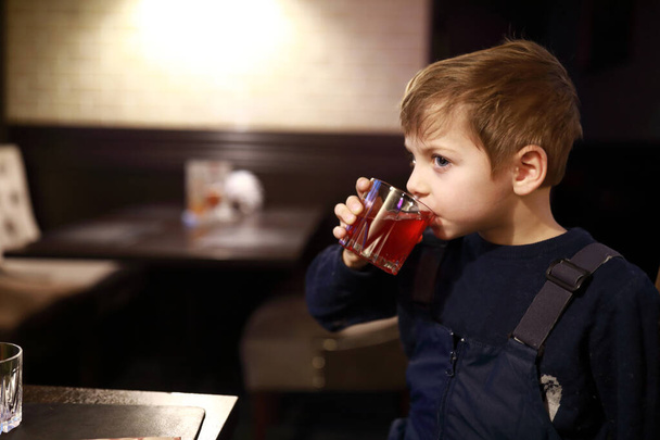 Portrait of kid drinking juice in restaurant - Фото, изображение