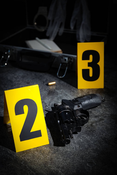 Shell casing, gun and crime scene markers on grey stone table - Foto, Imagen