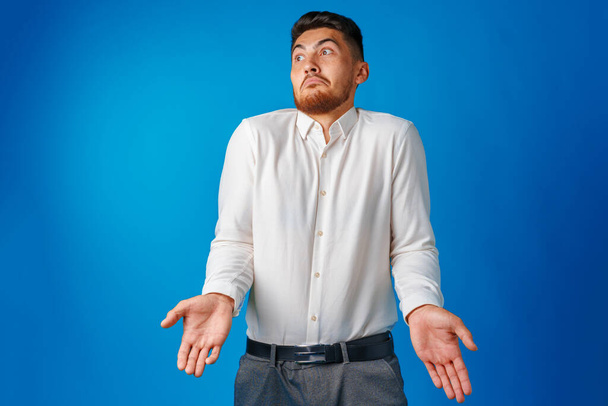Clueless businessman gesturing he doesnt know against blue background - Foto, Bild