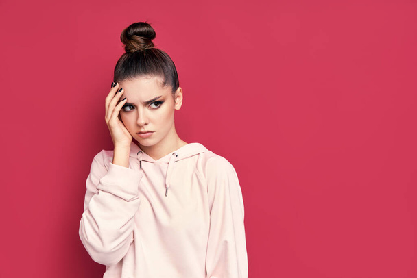 Young caucasian brunette upset woman looking at copy space on pink background. - Foto, Imagen