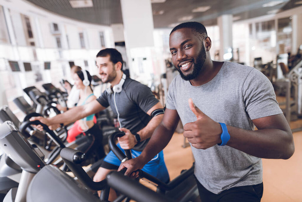 People at gym go smiling and raised a finger up. - Фото, изображение