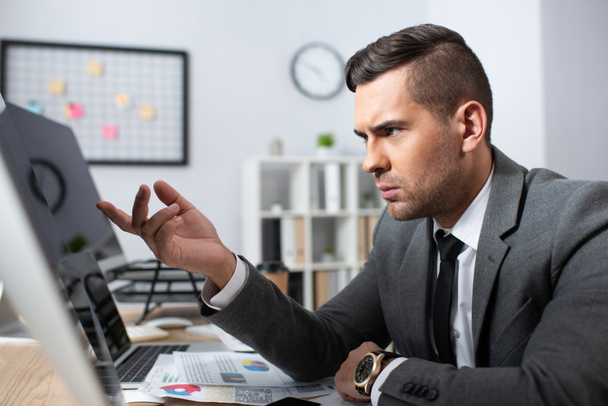 serious businessman pointing with finger at monitor on blurred foreground - Photo, image