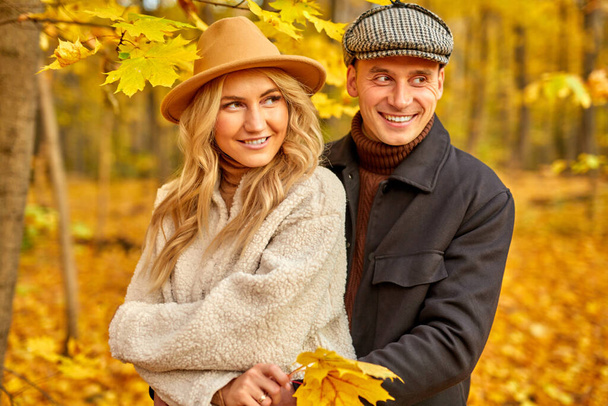 married couple in autumn-style clothes walk outdoors in autumn forest - Valokuva, kuva