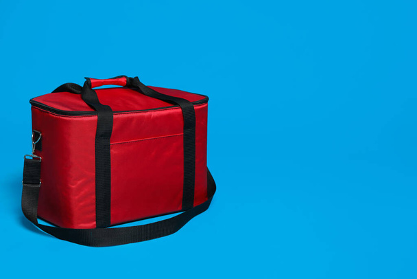 Modern red thermo bag on light blue background. Space for text - Zdjęcie, obraz