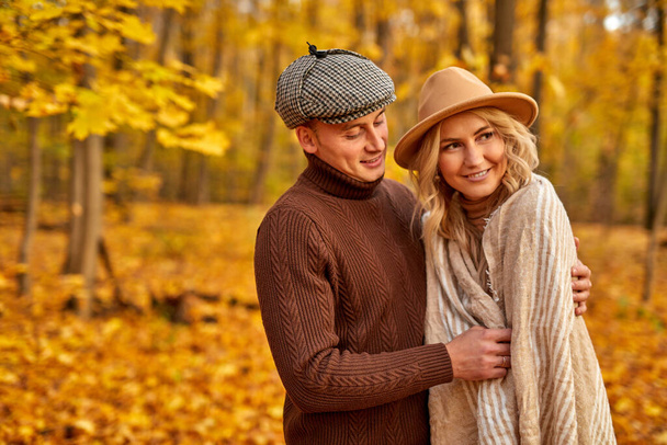 married couple in autumn-style clothes walk outdoors in autumn forest - Fotó, kép