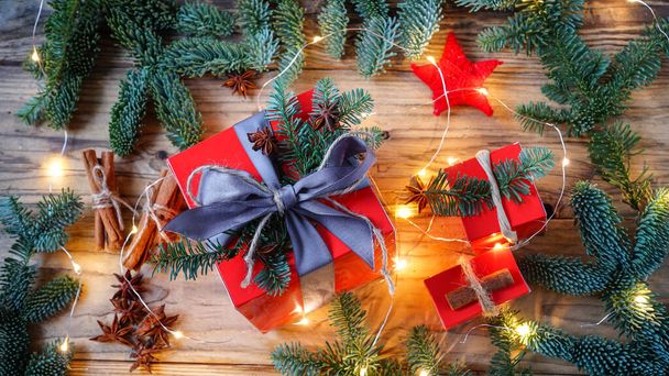 drei große und zwei kleine Geschenke auf einem hölzernen Hintergrund mit Weihnachtsbaum und Neujahrsdekor - Foto, Bild