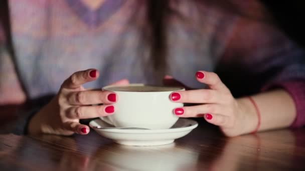 Женщина с латте на деревянном столе. Женщина с красными ногтями держит кофе в руках. - Кадры, видео