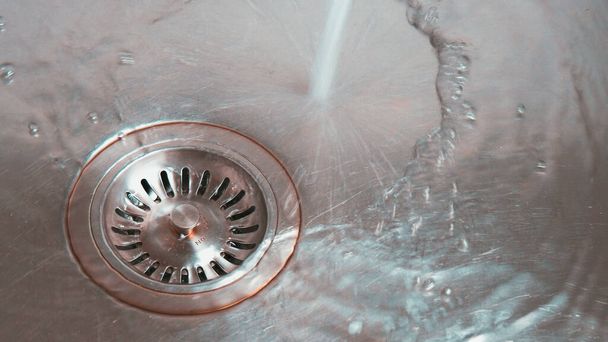 Metal sink with water going down drain. Close up.  - Photo, Image