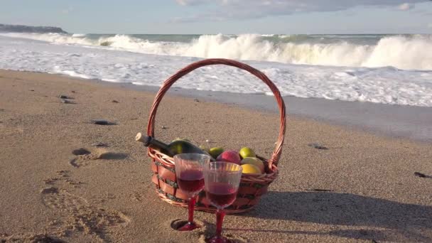 Pique-nique au bord de la mer. couverture, panier, bouteille de vin, deux verres avec vin rouge. - Séquence, vidéo