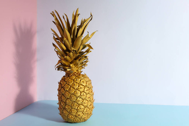 Golden pineapple on color background, space for text. Creative concept - Фото, зображення