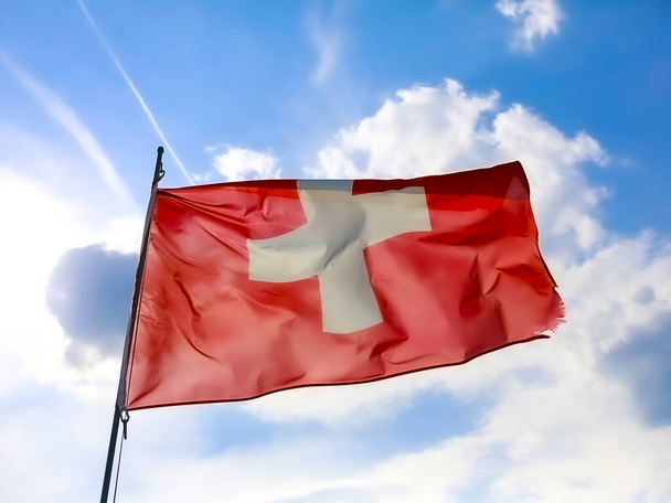Svájci zászló lengett a kék ég felett. Kiváló minőségű fénykép - Fotó, kép