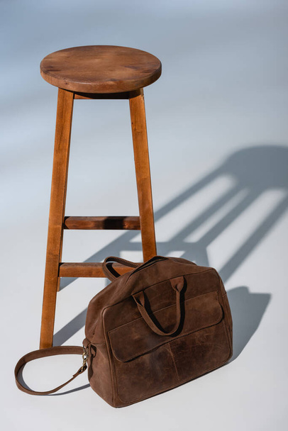 teczka skórzana w pobliżu drewnianego krzesła na szarości - Zdjęcie, obraz