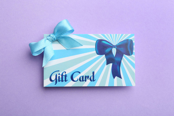 Gift card with bow on violet background, top view - Foto, imagen