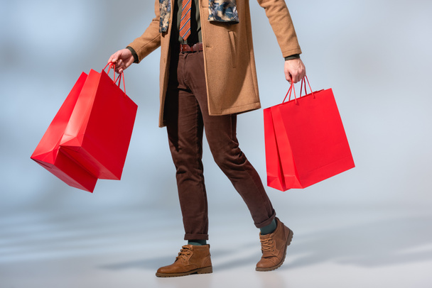 partial view of customer in coat holding paper bags on grey - Foto, Imagem