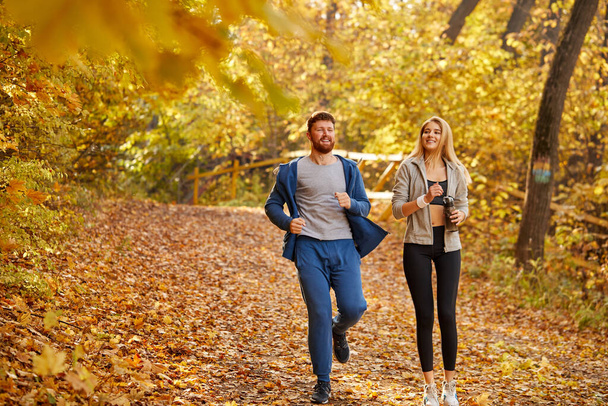 cheerful friends running in the autumn forest or park - Fotografie, Obrázek