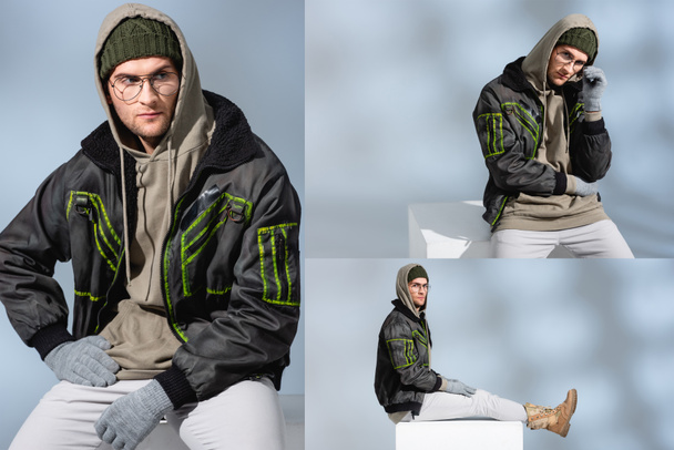 collage of trendy man in hat, gloves and parka with hand on hip sitting on white cube and adjusting glasses on grey  - Фото, изображение