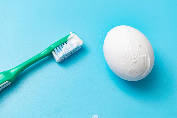 Brushing a chicken egg with a toothbrush. Caries prevention concept. - Photo, image