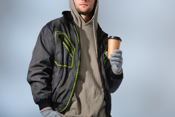 cropped view of fashionable man in anorak holding paper cup isolated on grey - Photo, Image