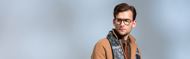hombre de moda en gafas, bufanda y abrigo de invierno mirando hacia otro lado en gris, pancarta - Foto, Imagen