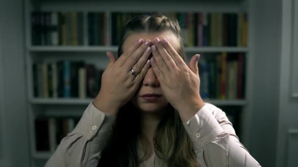 Portret van een jonge blanke vrouw die de ogen sluit met de handen in de binnenruimte - Video