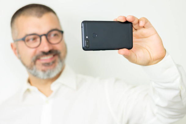 Handsome bearded man wearint shirt and glasses taking selfie or communicates online - Photo, image