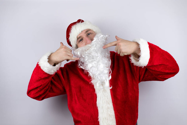 Hombre vestido de Santa Claus de pie sobre fondo blanco aislado haciendo el gesto llámame con sus manos - Foto, Imagen