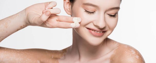 Lächeln junge schöne Frau mit Vitiligo Anwendung kosmetischer Creme isoliert auf weiß, Banner - Foto, Bild