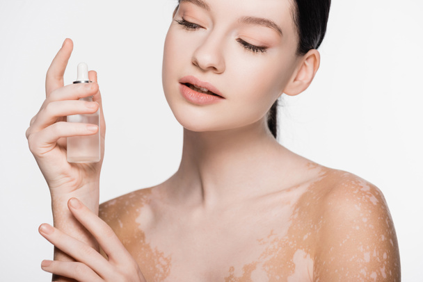 young beautiful woman with vitiligo holding serum isolated on white - Foto, immagini