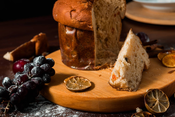 Traditional Christmas panettone with dried fruits on rustic background. Panettone is the traditional Italian dessert for Christmas - Photo, Image
