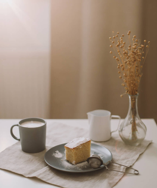 Piece of homemade cake with a cup of cappuccino on table with linen tablecloth. Morning breakfast. Top view, flat lay, copy space - Foto, Imagem