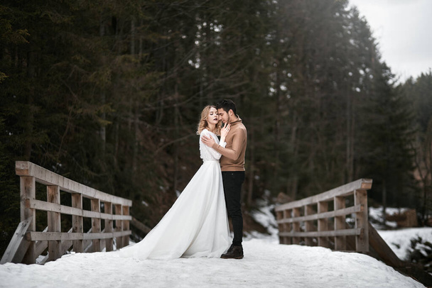 bruidegom en bruid wandelen in winterbos park. buiten besneeuwde dag - Foto, afbeelding