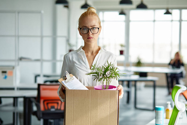sad dismissed female worker is taking her office supplies from office - Foto, imagen