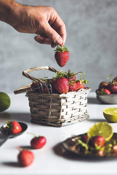 fresh strawberries in a basket on a white wooden table - Fotó, kép