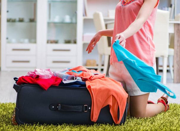 Kobieta próbuje zmieścić wszystkie ubrania do suitacase przed wakacjami - Zdjęcie, obraz
