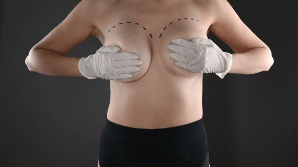 La niña sostiene su pecho desnudo con las manos, con un grito de un rotulador. Foto de alta calidad - Foto, Imagen