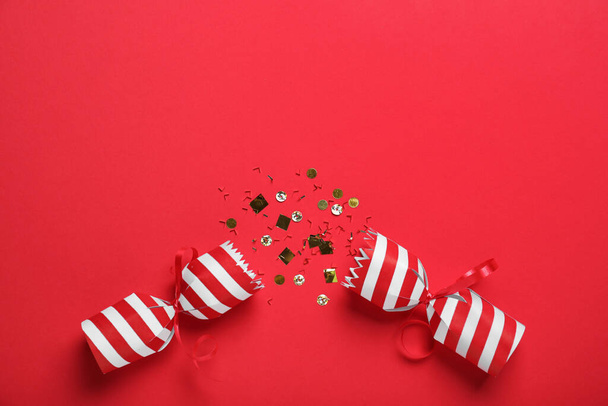 Open Christmas cracker with shiny confetti on red background, top view. Space for text - Photo, image