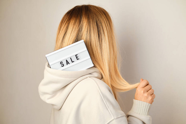 Light box with inscription SALE in the hands of a girl. Season sale, holiday shopping. Special offer for consumers. Advertisement promotion with discount. Marketing promotion of products and services - 写真・画像