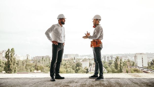 Foreman and engineer discussing project on construction site - Фото, изображение