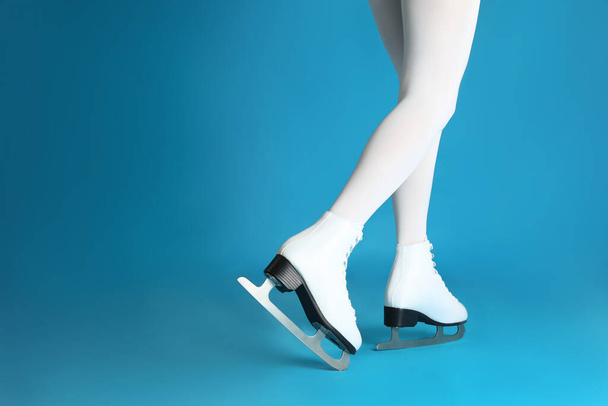 Woman in elegant white ice skates on light blue background, closeup of legs. Space for text - Fotó, kép