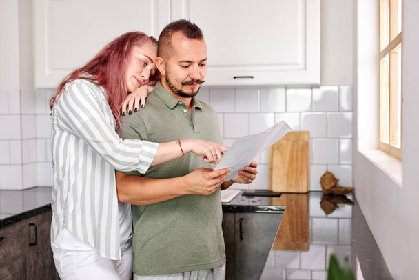 lovely caucasian couple checking bills documents in the kitchen - Foto, afbeelding
