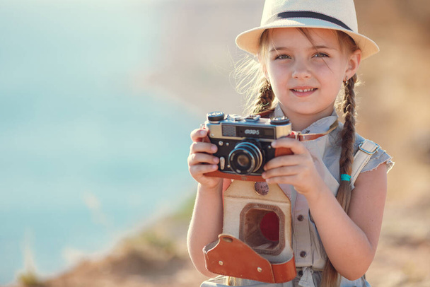 Kind Mädchen Reisenden. Reise allein. Mädchen, das mit Kamera und Koffer auf dem Meer in der Natur unterwegs ist. Reisen, Urlaub, Urlaub - Foto, Bild