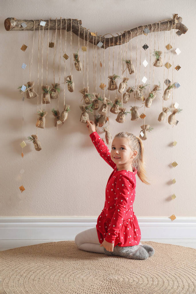 Little girl taking gift from New Year advent calendar indoors - Φωτογραφία, εικόνα