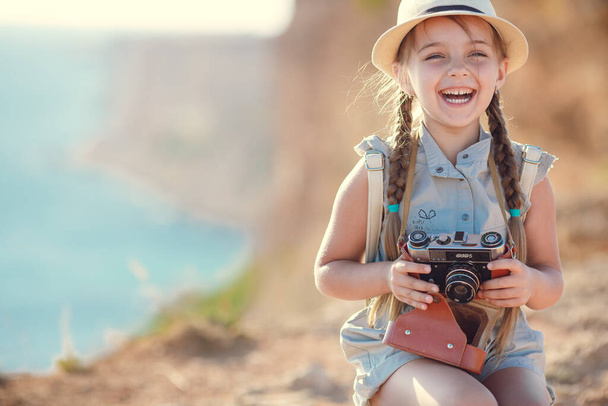 child girl traveler. trip alone. girl walking with camera and suitcase on nature by sea. travel, vacation, holidays - Valokuva, kuva