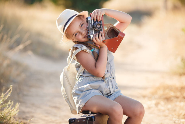 child girl traveler. trip alone. girl walking with camera and suitcase on nature by sea. travel, vacation, holidays - Valokuva, kuva