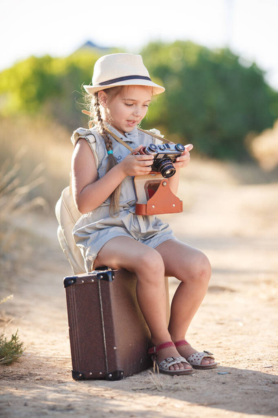 child girl traveler. trip alone. girl walking with camera and suitcase on nature by sea. travel, vacation, holidays - Foto, afbeelding