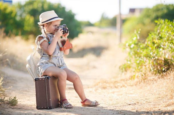 child girl traveler. trip alone. girl walking with camera and suitcase on nature by sea. travel, vacation, holidays - Foto, imagen