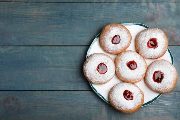 Hanukkah doughnuts with jelly and sugar powder served on blue wooden table, top view. Space for text - Фото, изображение