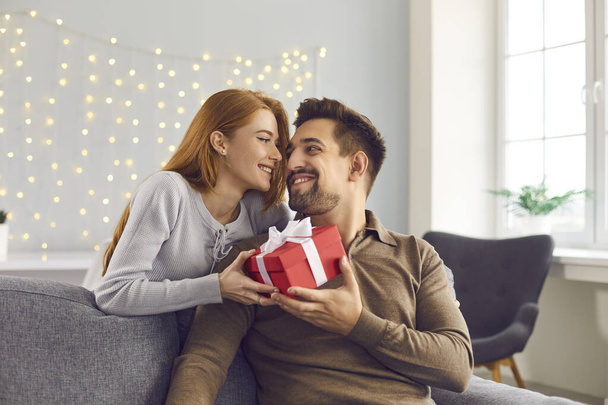 Happy young man holding Valentine gift, smiling and thanking his girlfriend for present - Фото, изображение