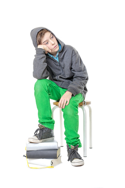 είναι λυπηρό αρσενικό κάθεται έφηβος με το ένα πόδι σε μια στοίβα από βιβλία, - Φωτογραφία, εικόνα